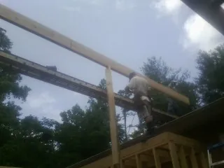 Carpenter setting a ridge beam over a new addition frame — Ice Dam Removal by Roofing Brothers in Groveland